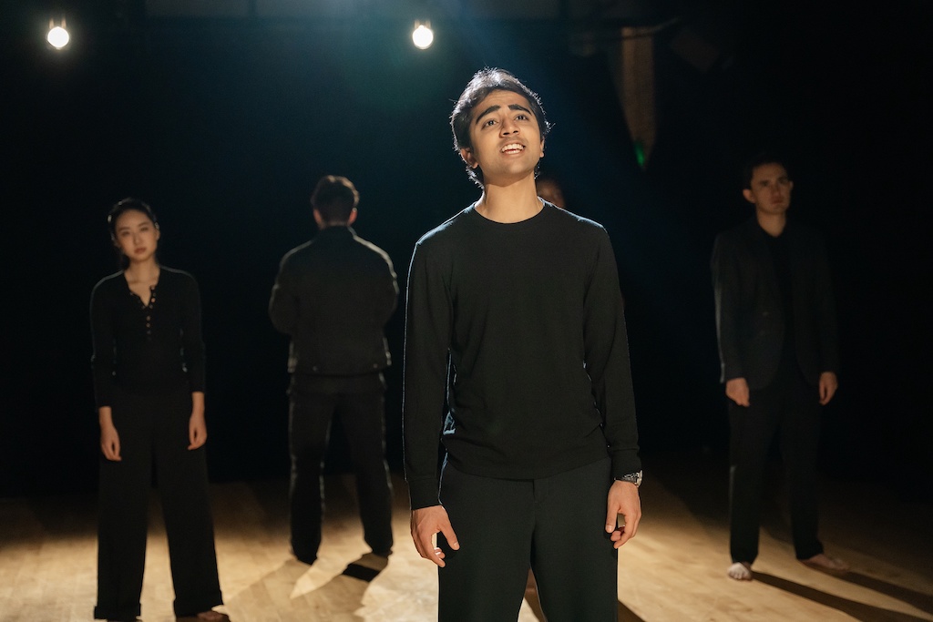 Actor stands with a hopeful expression on his face in mid-performance while three other actors stand behind him during the final presentation of The Winter's Tale.